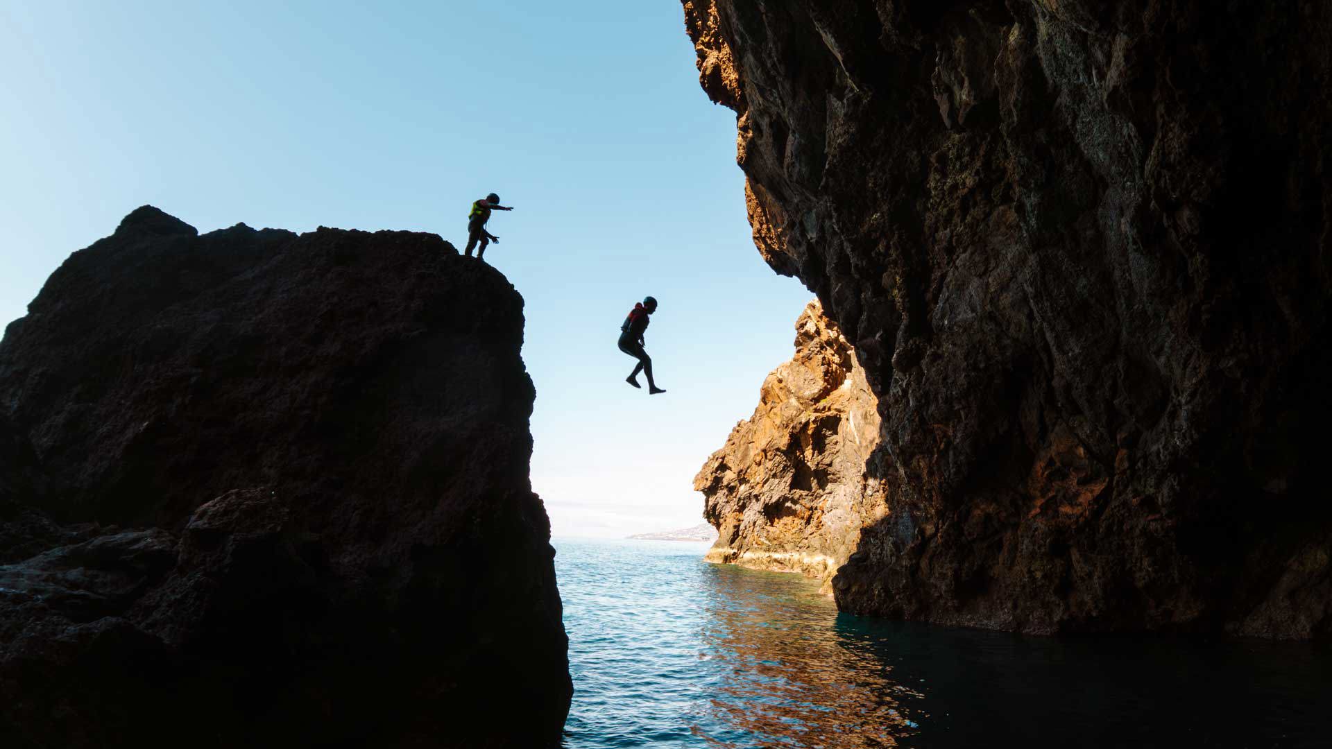 Dos personas saltando al mar durante una actividad de coasteering, en la isla de Madeira.