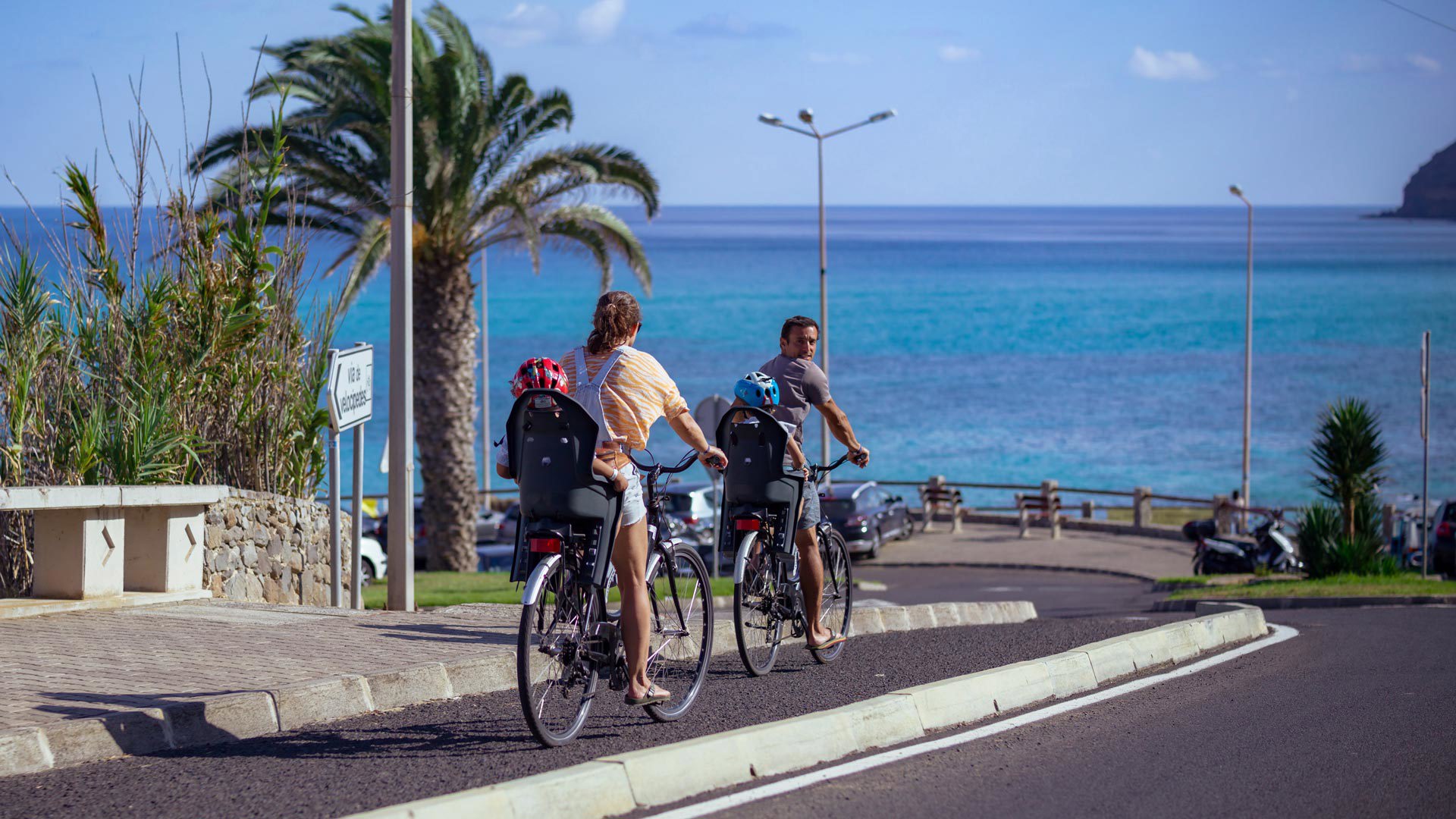 Familia paseando en bicicleta en Porto Santo, con los padres pedaleando y los hijos detrás.