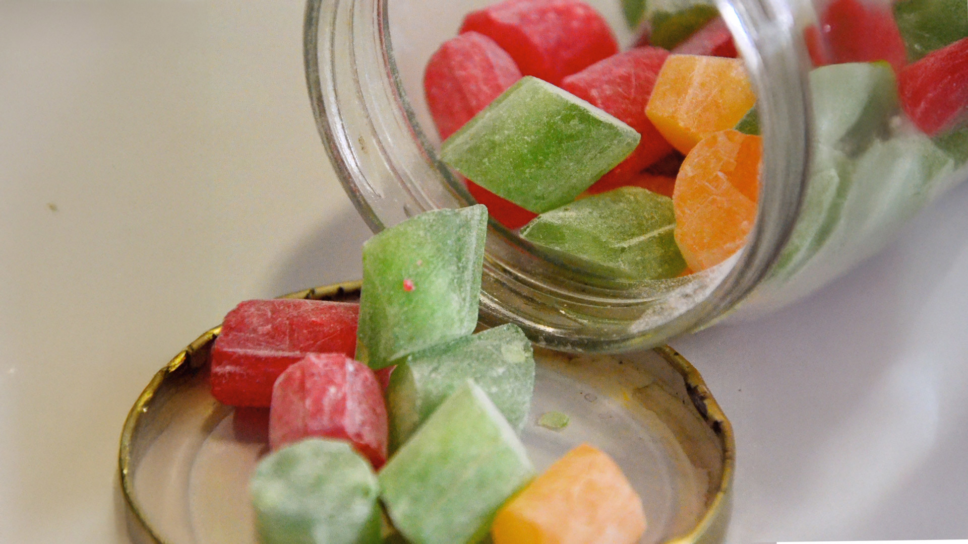 Rebuçados de funcho coloridos num frasco transparente.