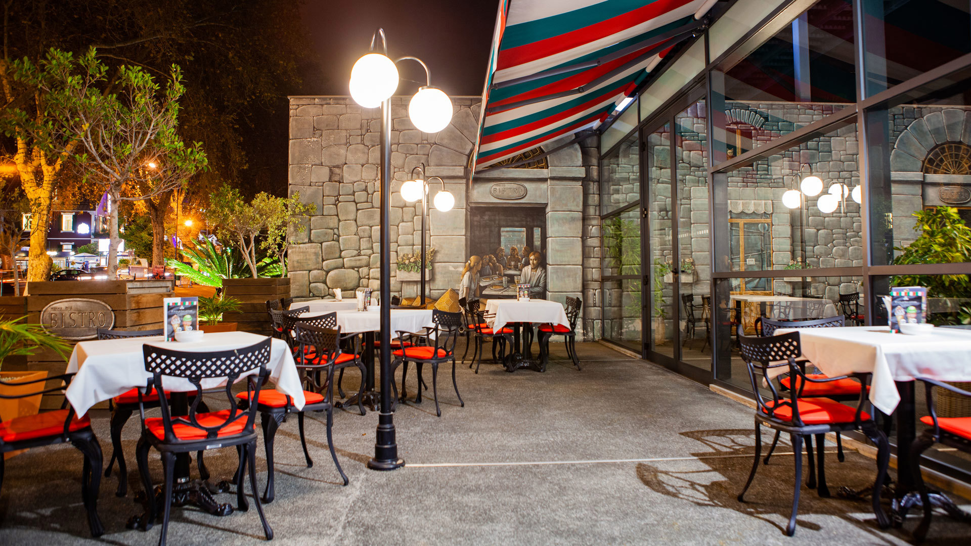 Terrasse bei Nacht mit roten Stühlen und eingeschalteten Lampen.