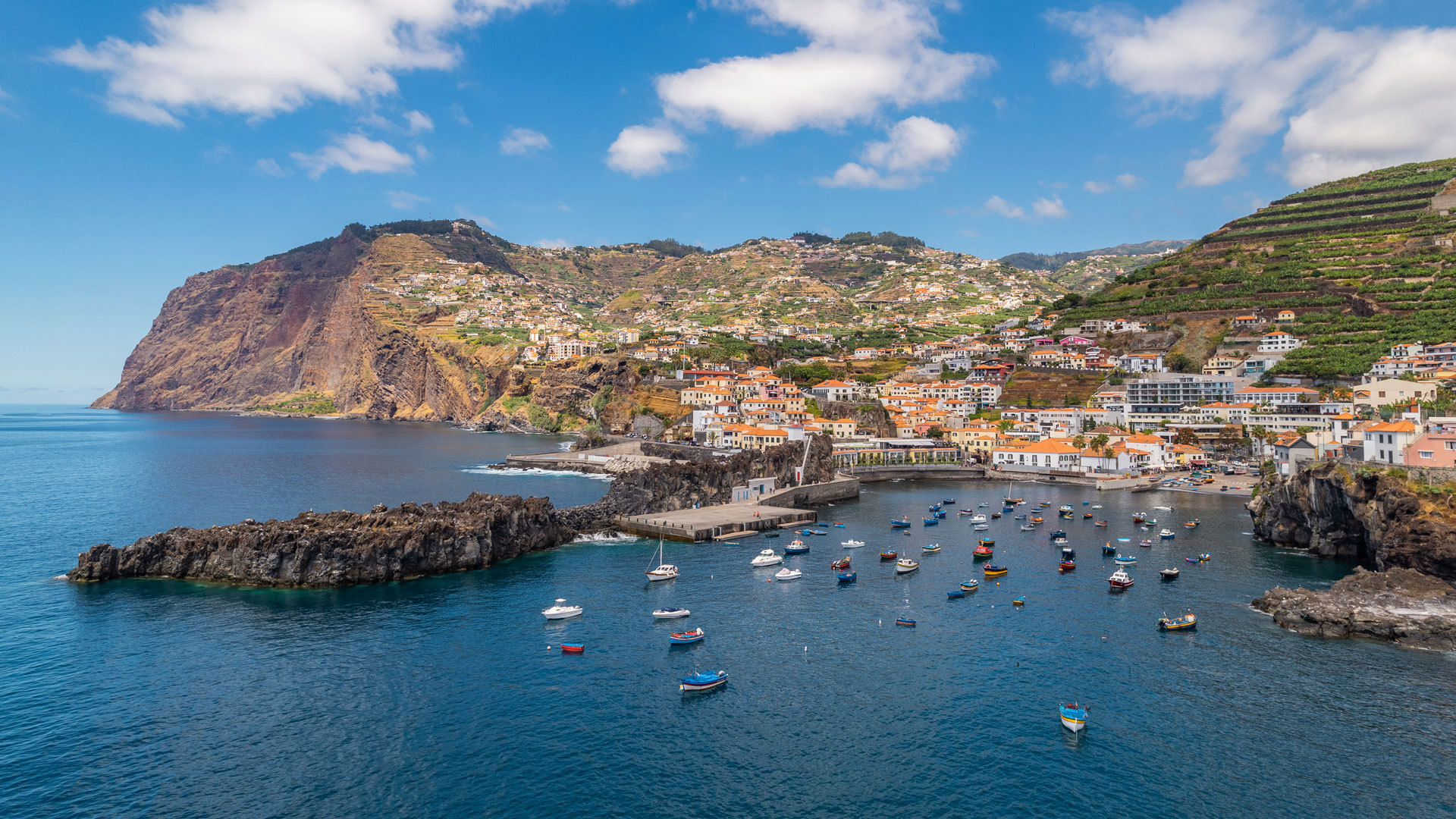 Baie de Câmara de Lobos avec mer calme et bateaux ancrés.
