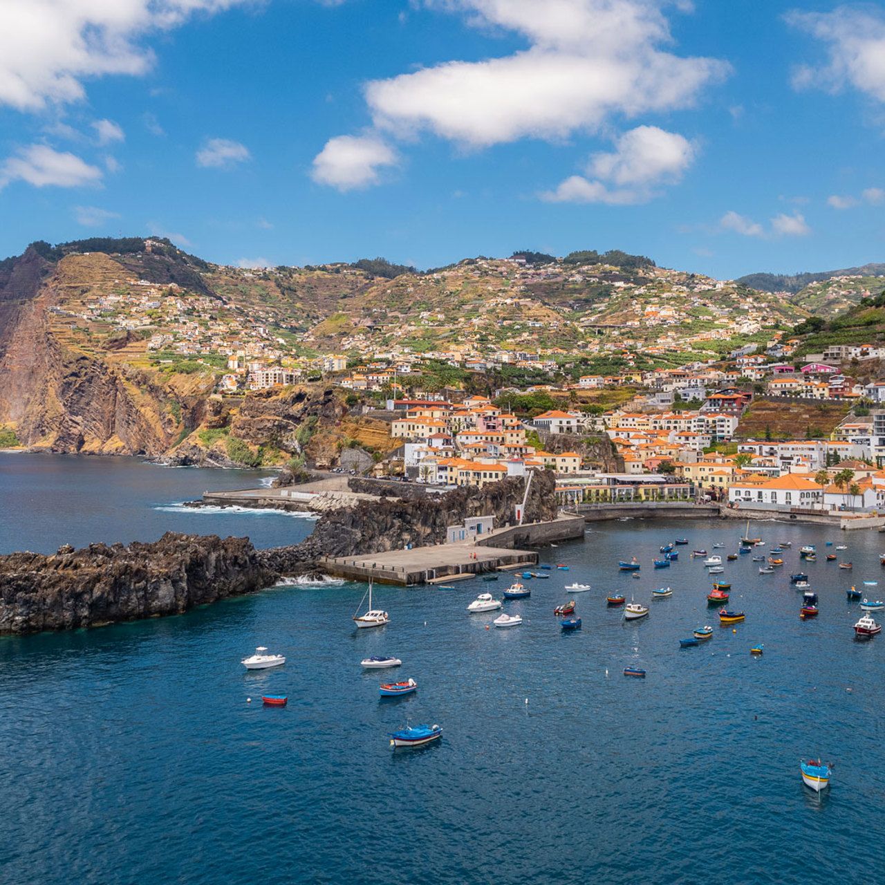Baía de Câmara de Lobos com mar calmo e barcos ancorados.