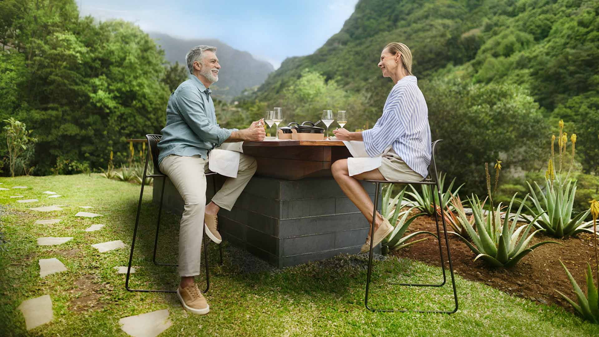 Pareja sentada bebiendo vino con la naturaleza de fondo.