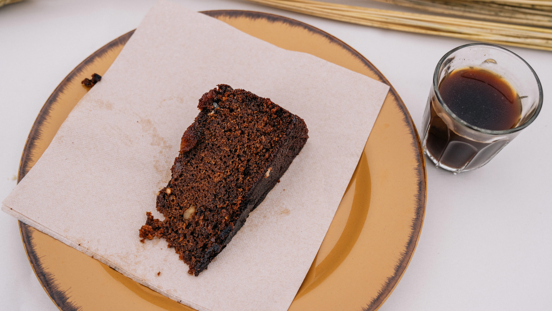 Fatia de bolo família servida num prato acompanhada por uma chávena de café.