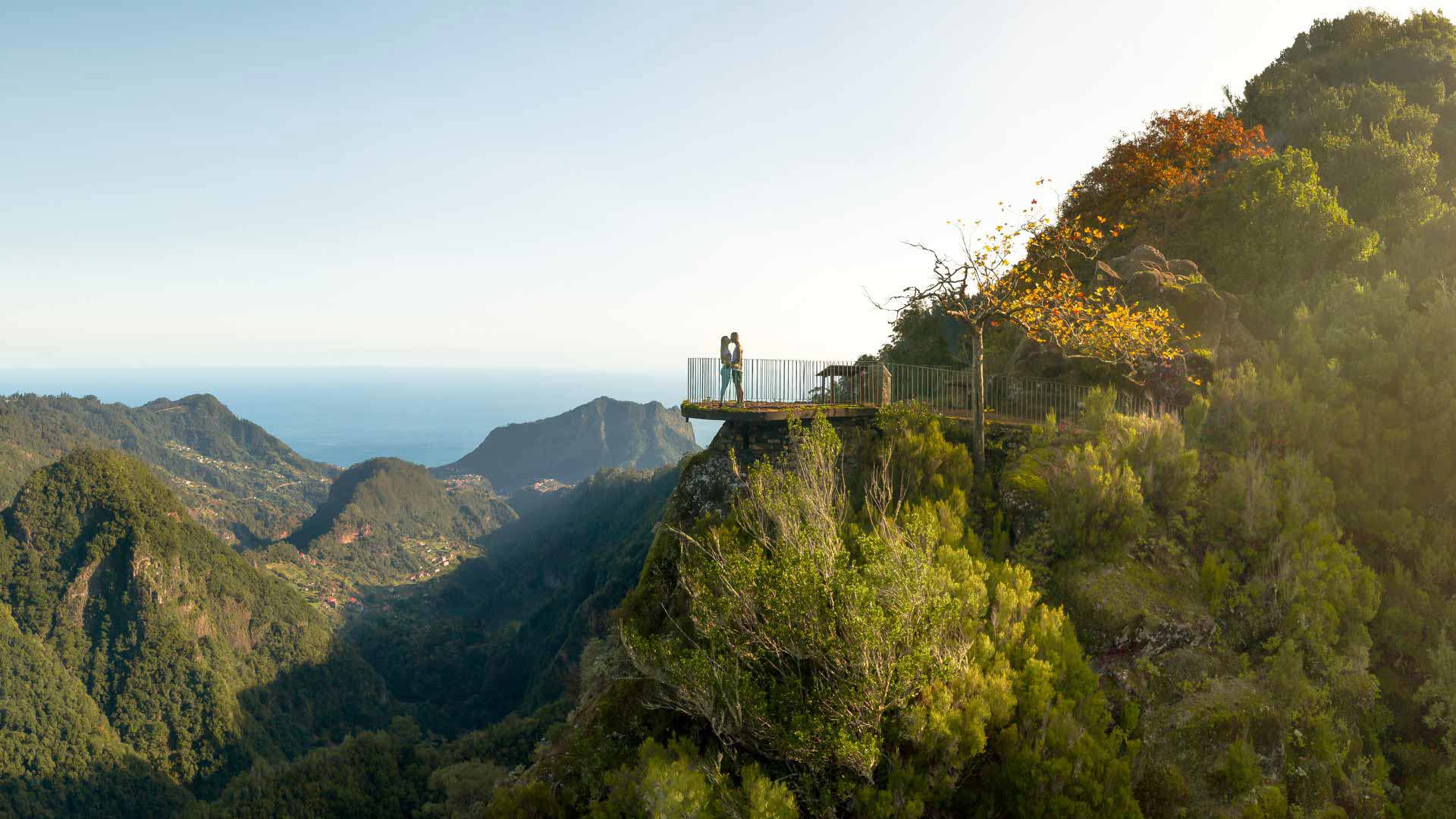Dos personas en el mirador en medio de las montañas con sol en Madeira.