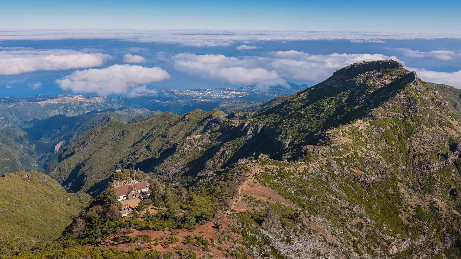 Grüner Berg mit Wolken unter blauem Himmel in Madeira.