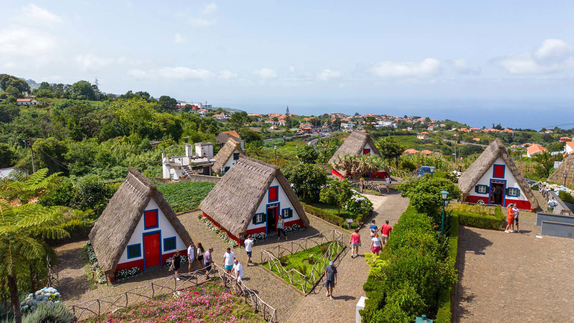 Casas triangulares com jardins e pessoas na Madeira.