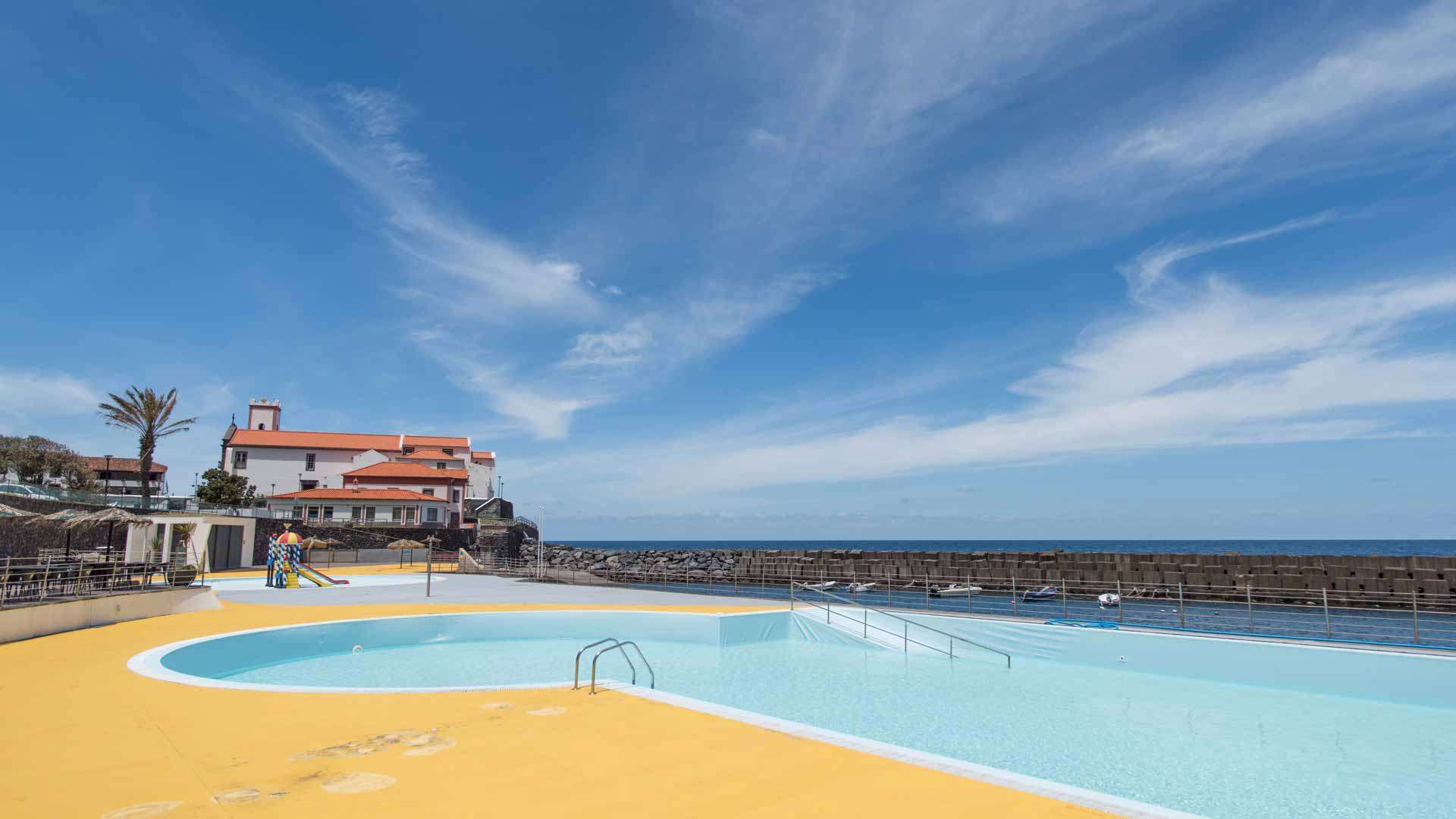 Pool mit blauem Himmel und Häusern im Hintergrund auf Madeira.