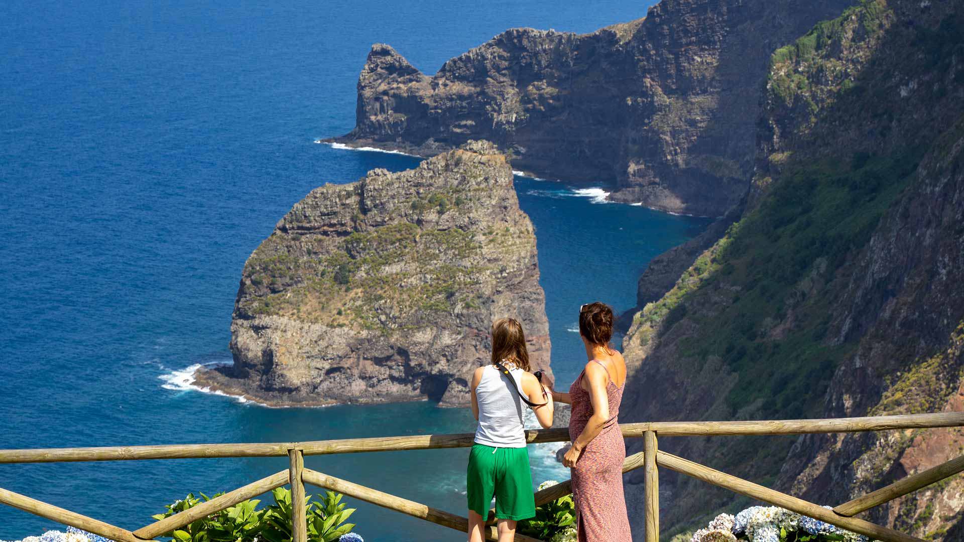 Two people observing islets and mountains in Madeira's landscape.