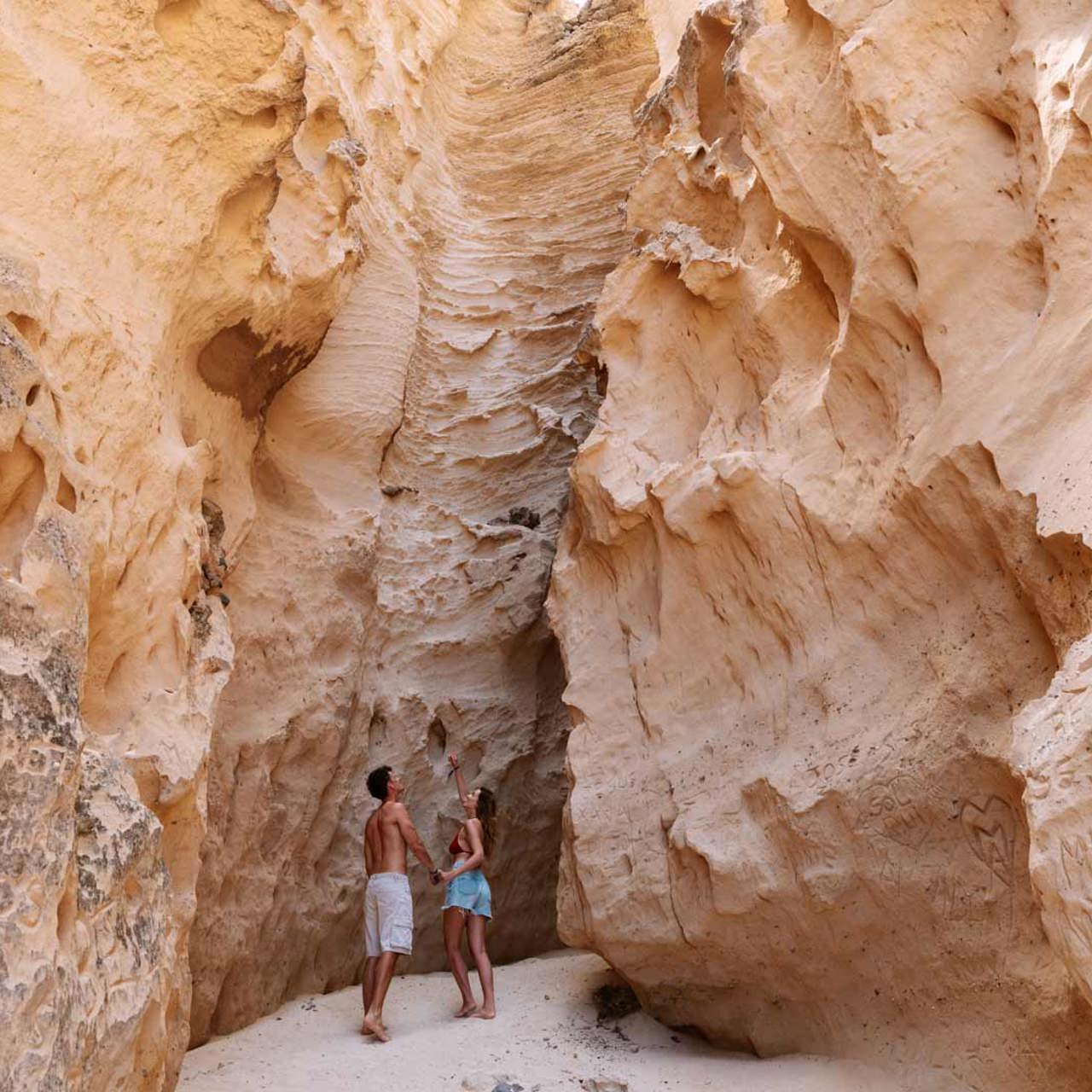 Pareja junto a una grieta geológica en zona arenosa