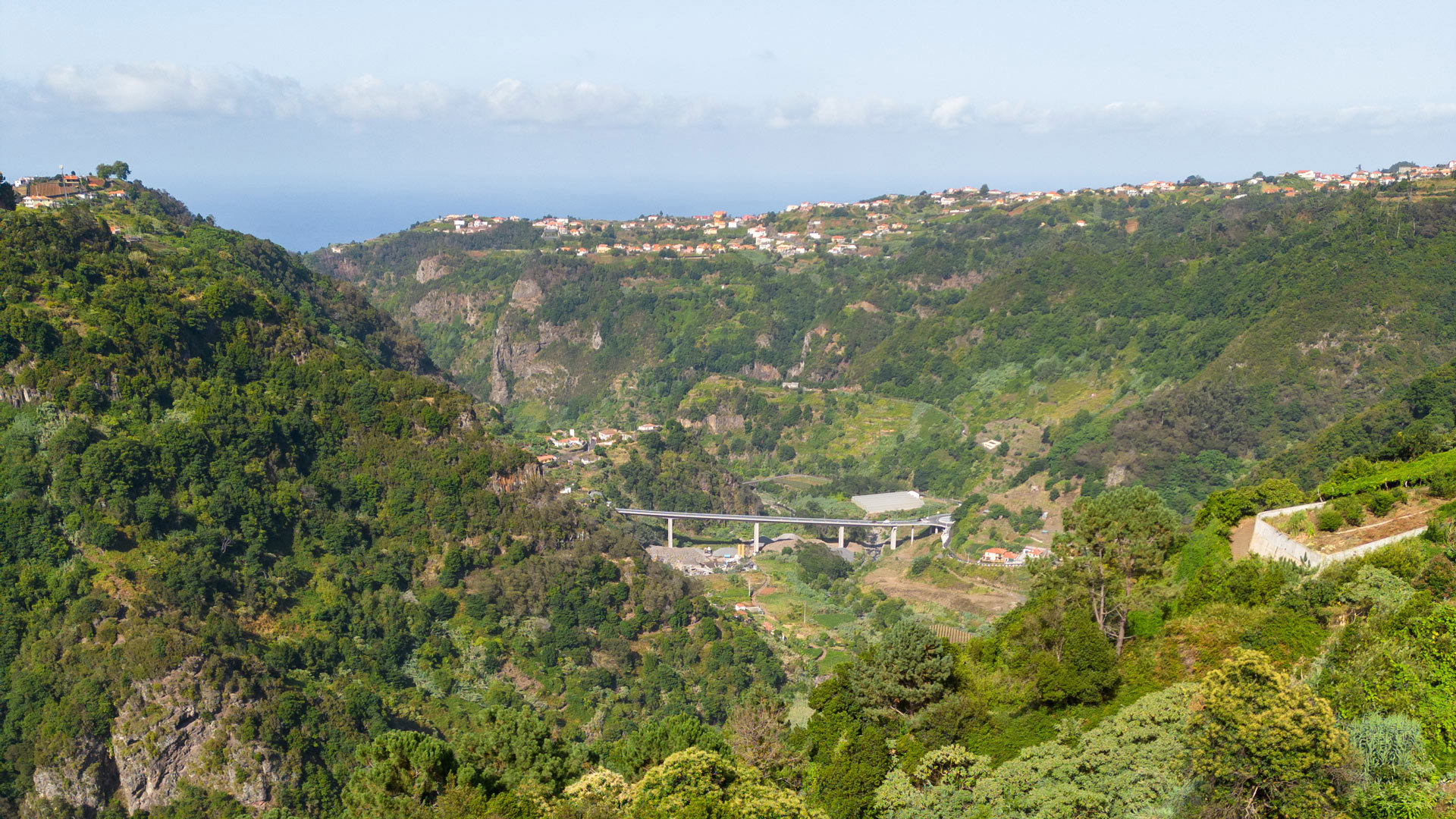 Montanhas e vale verde com casas ao longe na Madeira.
