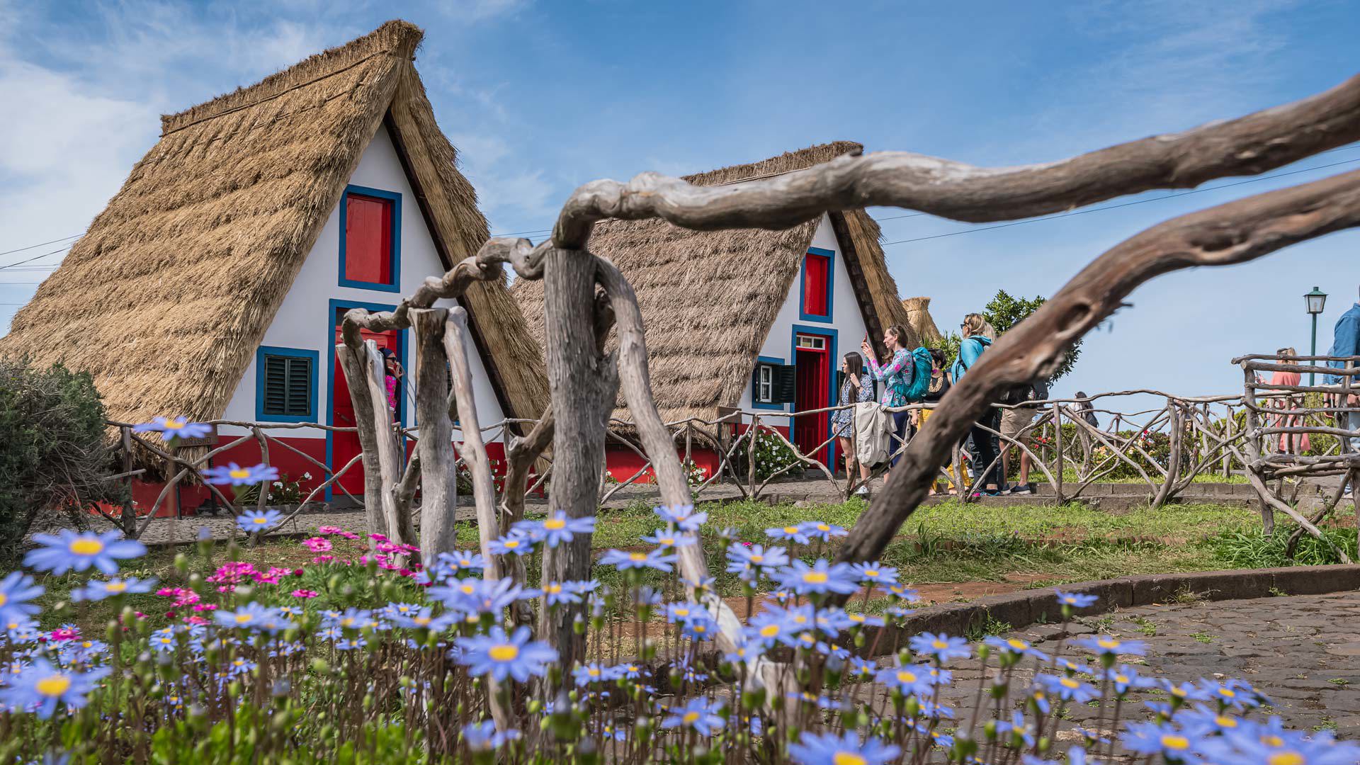 Casas tradicionais com pessoas próximas e vedação de madeira na Madeira.