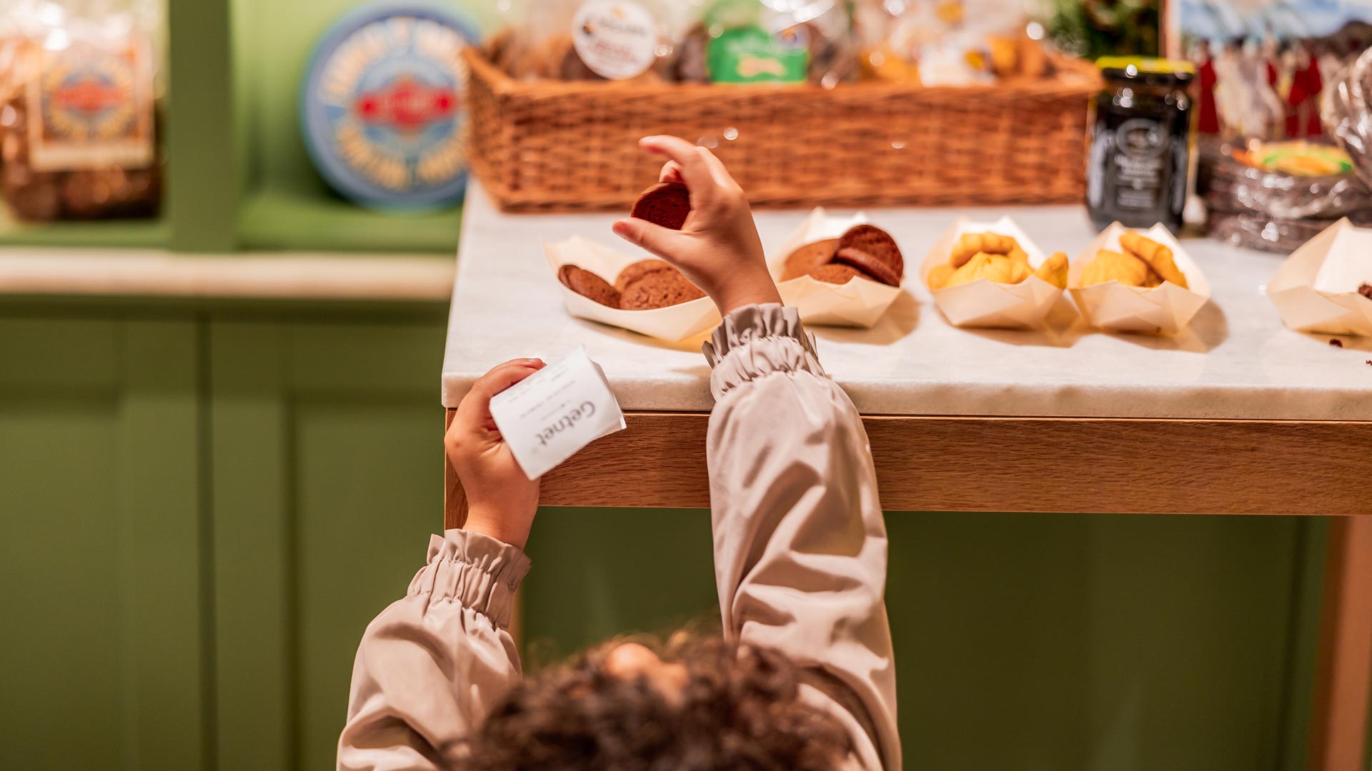 Child taking a broa from a table with traditional Madeiran broas and delicacies at the Madeira Tourism Office in Lisbon.
