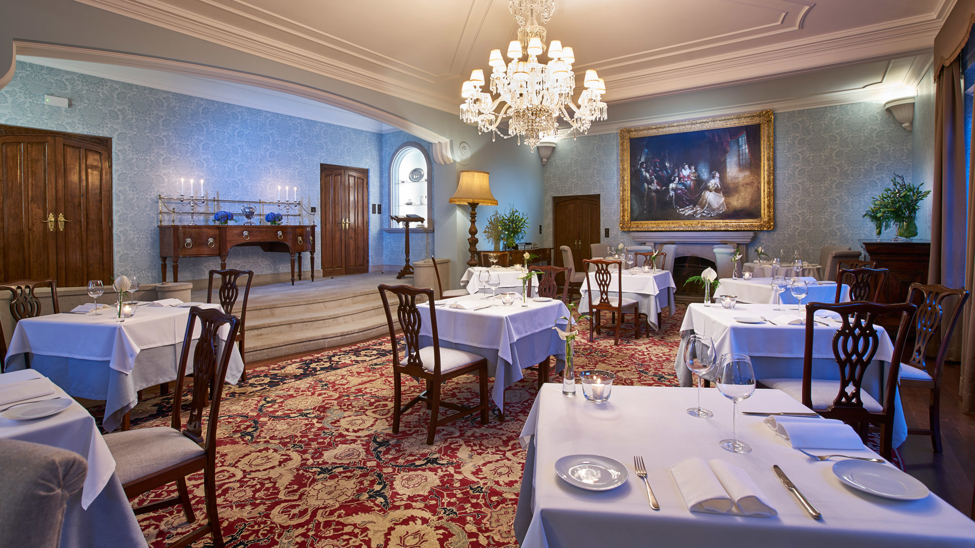 Raum dekoriert mit gedeckten Tischen, Stühlen und zentraler Lampe.