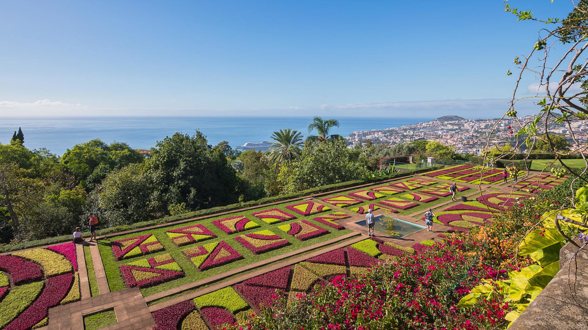 Jardim com padrões coloridos variados junto ao mar.