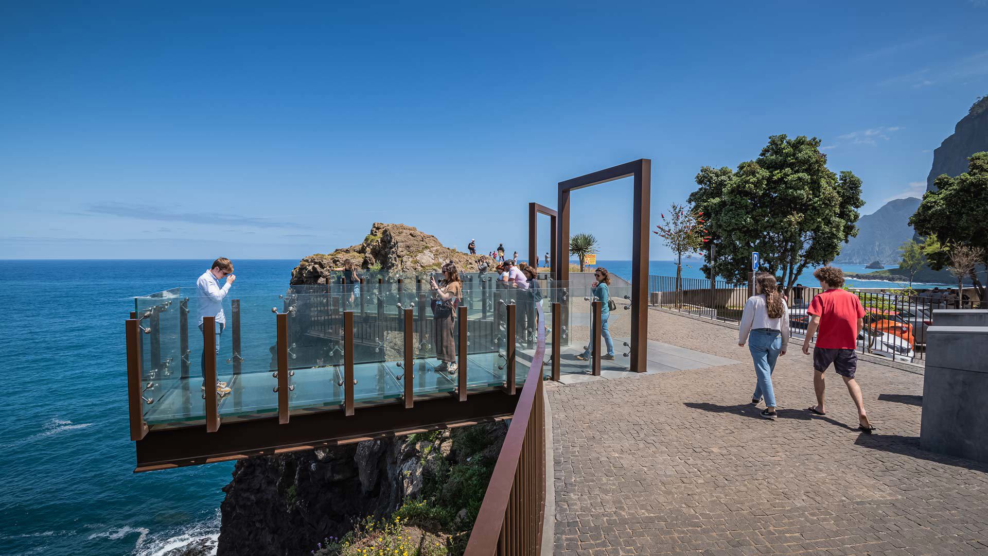 Personas en un mirador de vidrio sobre el mar y las rocas en la costa de Madeira.